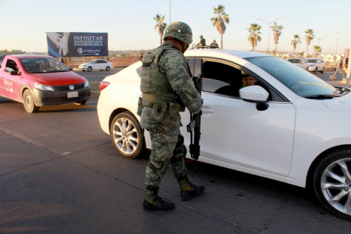 Image of a soldier talking to an automobile passenger at a checkpoint
